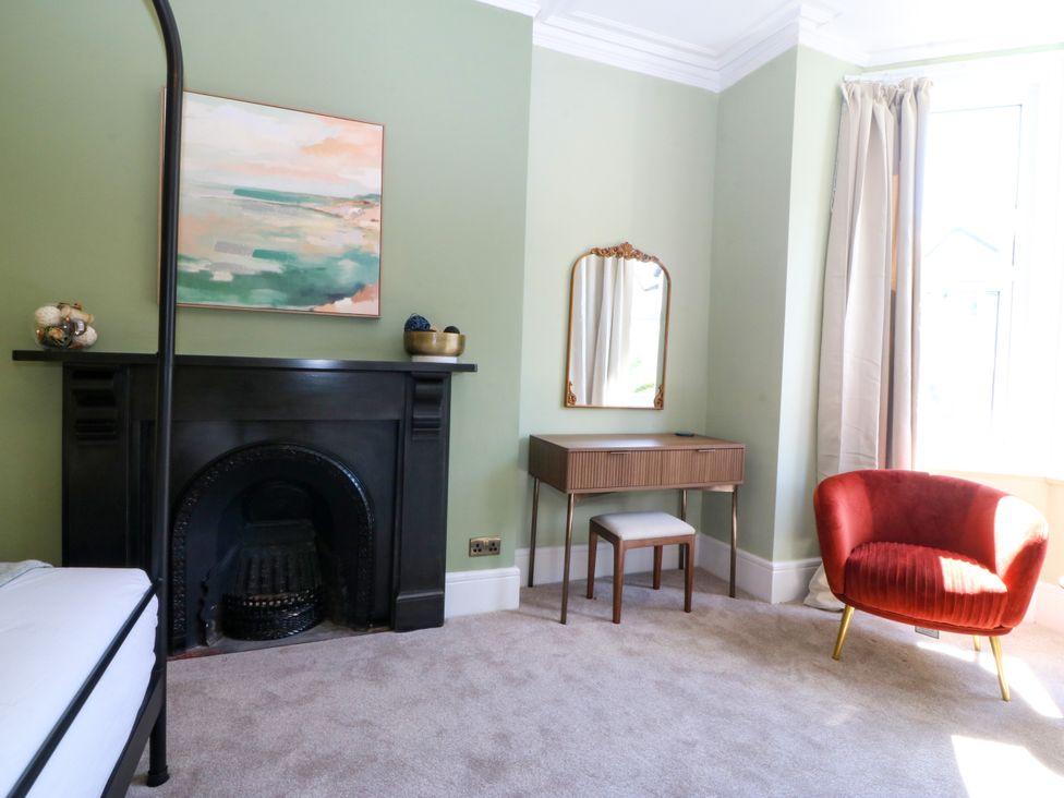 A bedroom with a fireplace and a mirror at Fox House in Llandudno