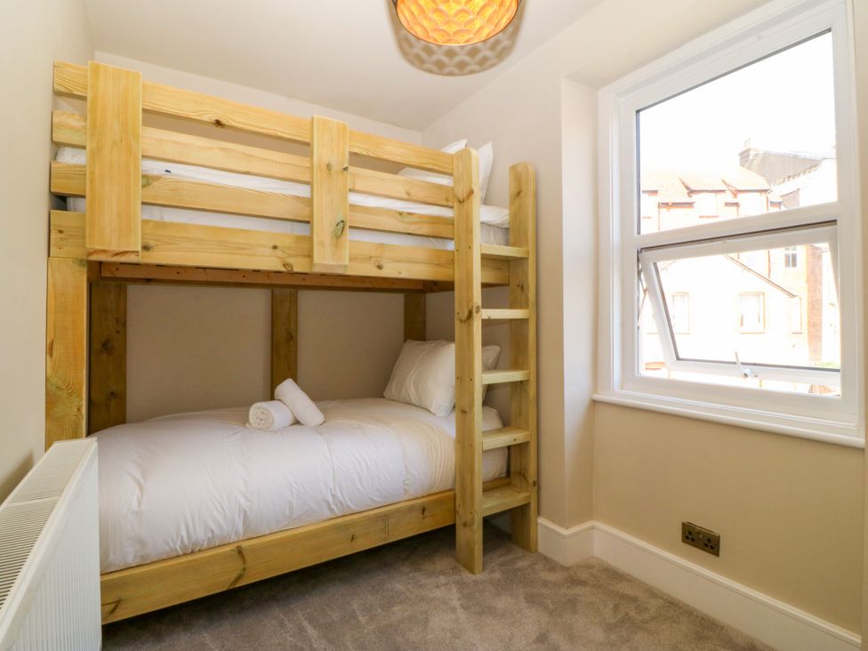 A bedroom with a bunk bed and a single bed at Fox House in Llandudno