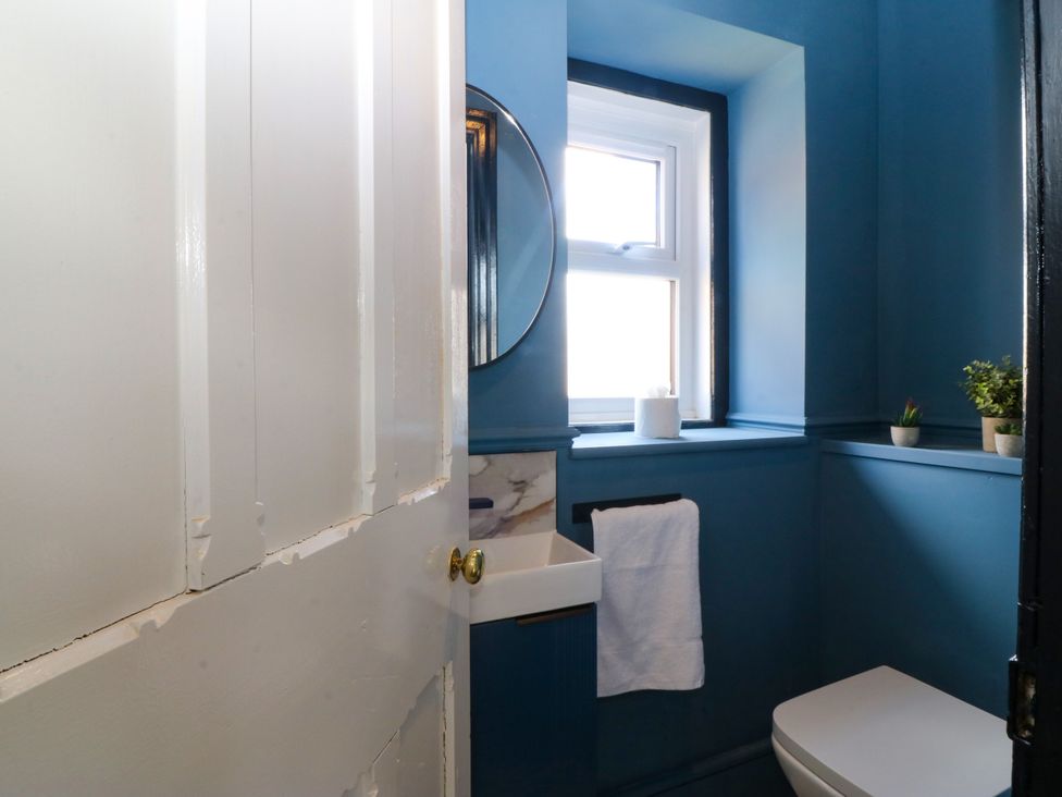 A bathroom with a toilet, sink and mirror at Fox House in Llandudno