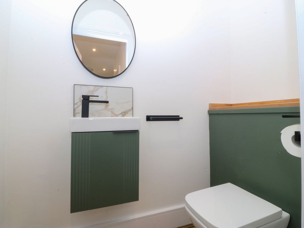 A bathroom with a sink, mirror, and toilet at Fox House in Llandudno