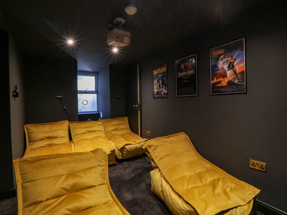 A home theater with yellow seating and movie posters at Fox House in Llandudno