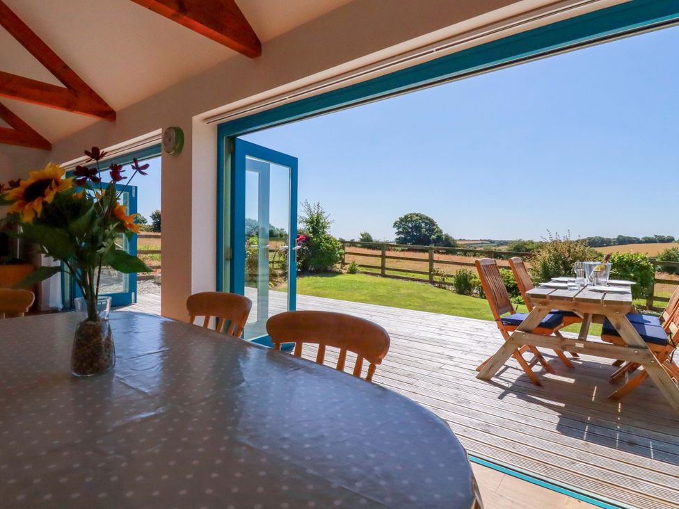 A dining room leading to a deck with outdoor seating at Little Chywoon Barn in Truro