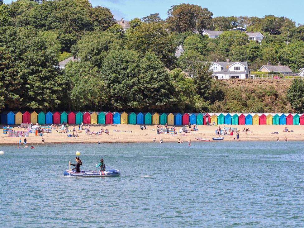 A beach with colorful beach huts and people enjoying the sun at 3 Glyn Y Mor Llanbedrog