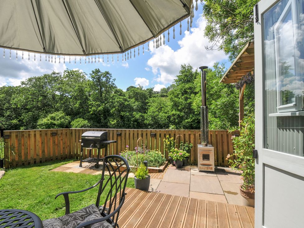 A garden patio with a barbecue grill and plants at The Highwood Hut near Liskeard