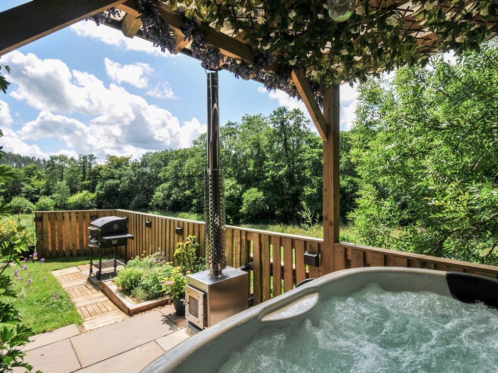 An outdoor area with a hot tub and grill at The Highwood Hut near Liskeard