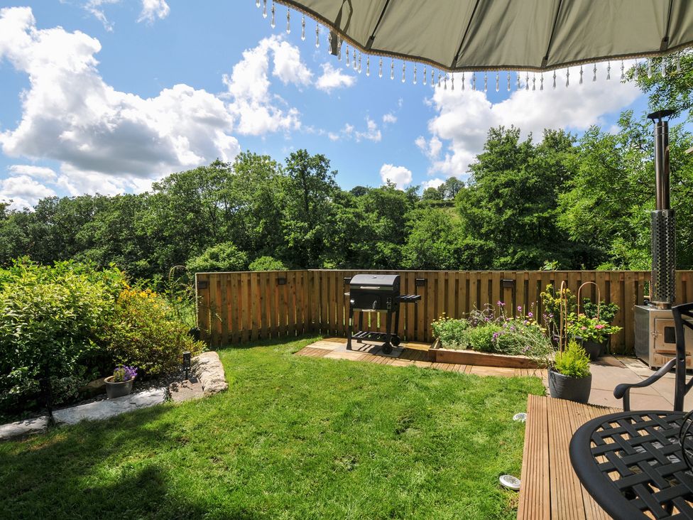 A garden with a grill, seating area and greenery at The Highwood Hut near Liskeard