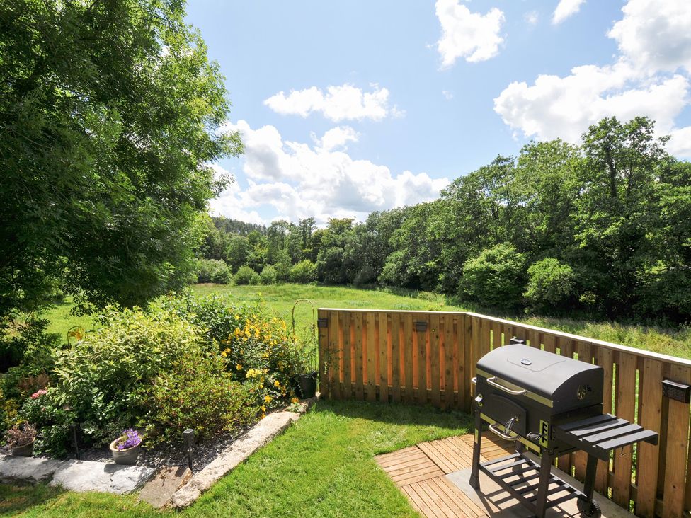 A garden with a grill and a view of trees at The Highwood Hut near Liskeard