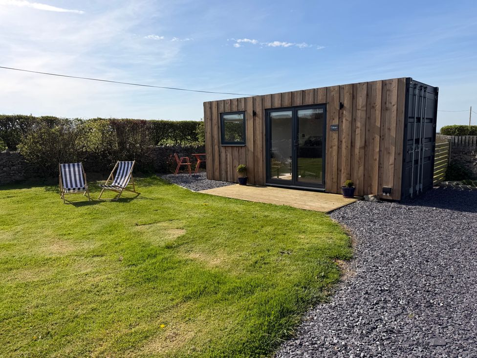 An outdoor area with a shipping container and chairs at Caban in Dothan near Gwalchmai