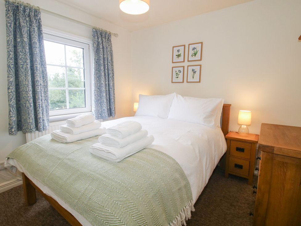A bedroom with a bed and towels at 2 Aqueduct Cottages Chirk Bank near Chirk