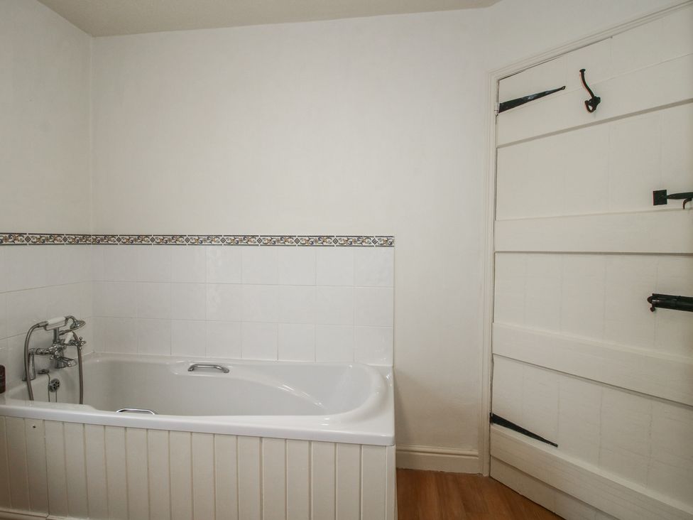 A bathroom with a bathtub and a door at 2 Aqueduct Cottages Chirk Bank near Chirk