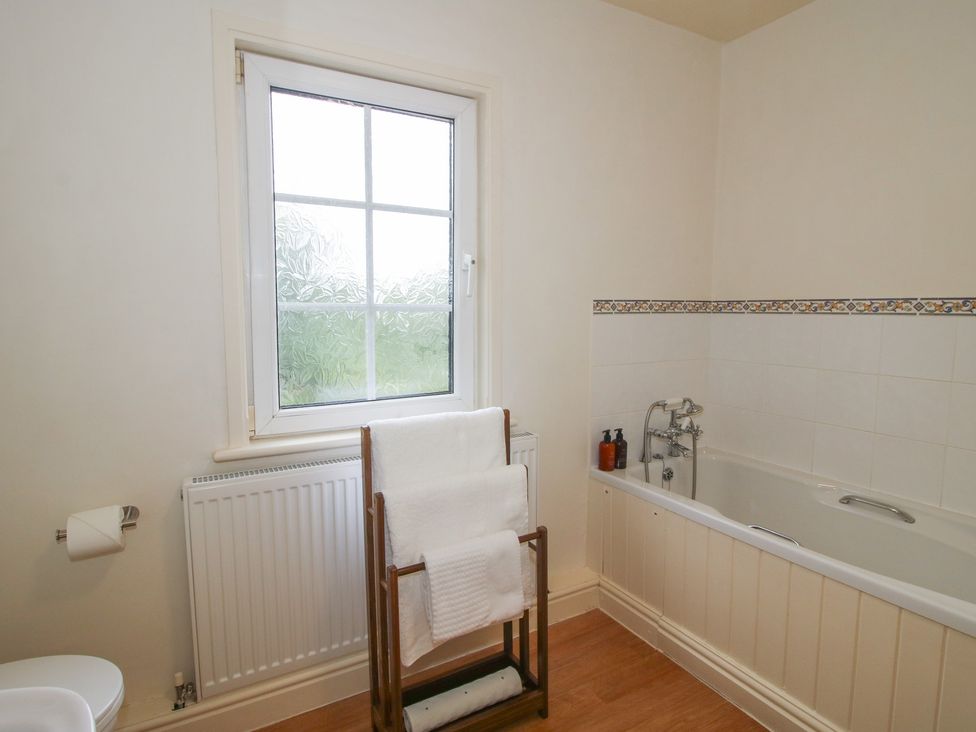A bathroom with a bathtub and towel rack at 2 Aqueduct Cottages Chirk Bank near Chirk