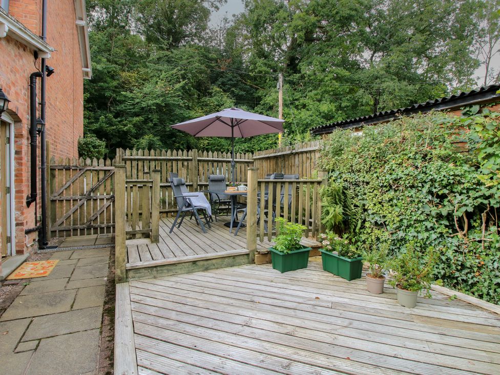 A deck area with table and chairs under an umbrella at 2 Aqueduct Cottages Chirk Bank near Chirk