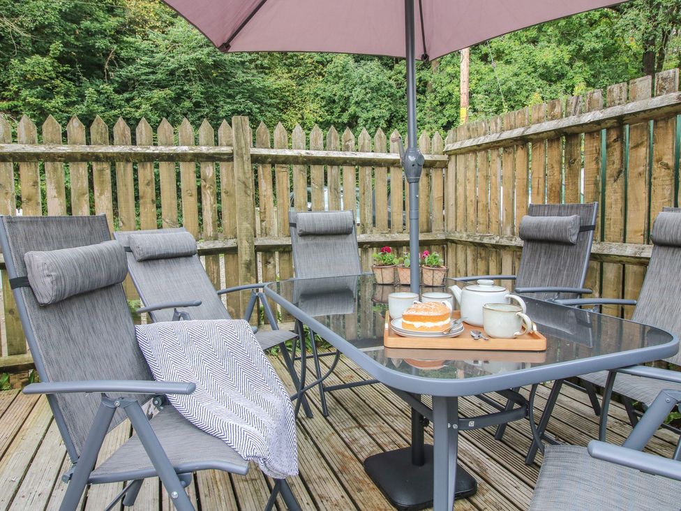 A patio with table and chairs under an umbrella at 2 Aqueduct Cottages in Chirk Bank near Chirk