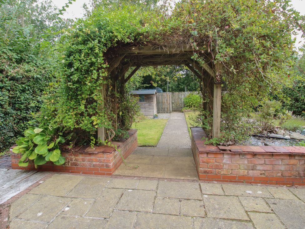 A garden with an archway leading to a grassy area at 2 Aqueduct Cottages in Chirk Bank near Chirk