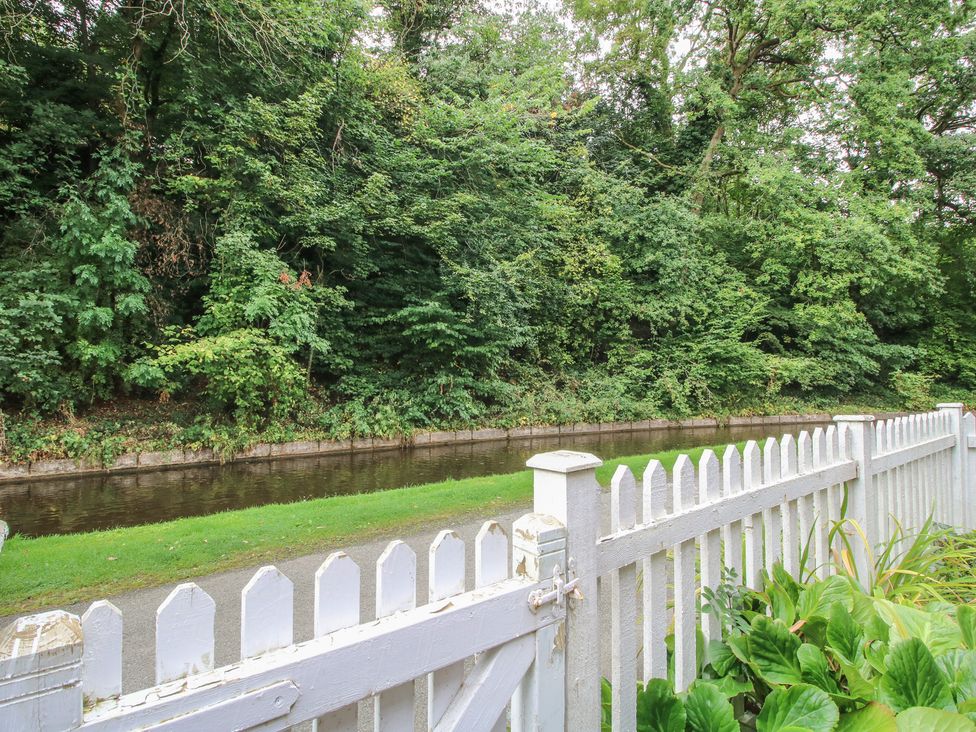 A view of a canal with a fence and surrounding greenery at 2 Aqueduct Cottages in Chirk Bank near Chirk
