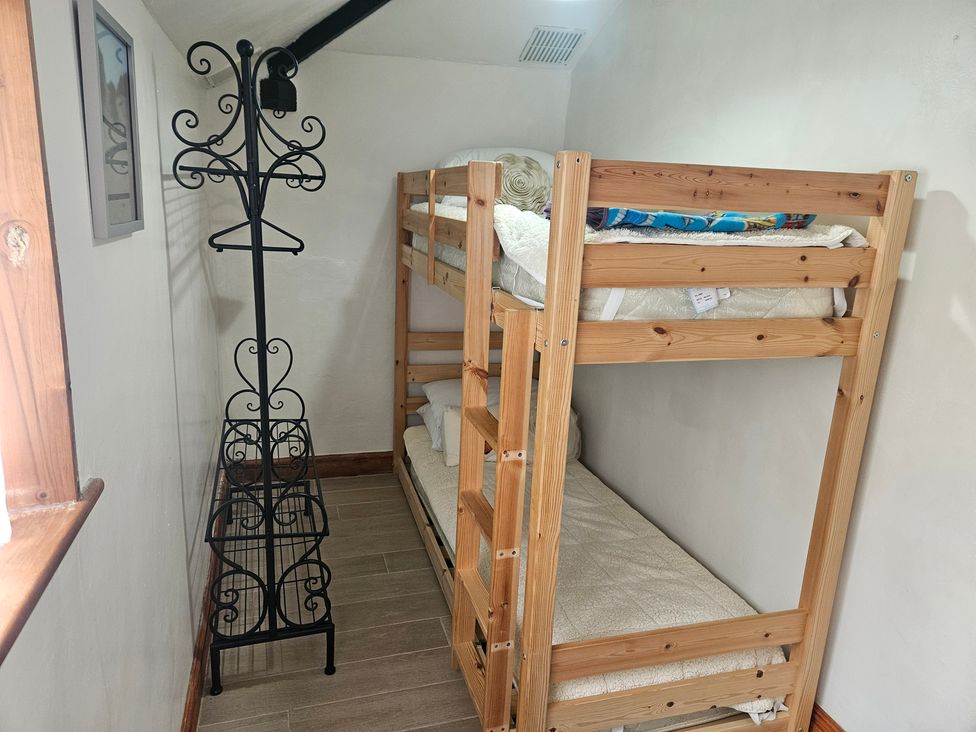 A bedroom with a bunk bed and a coat rack at The Coach House in Redruth
