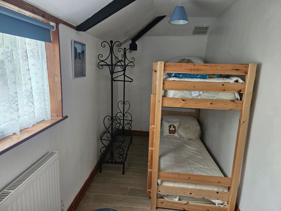 A bedroom with a bunk bed and curtains at The Coach House in Redruth