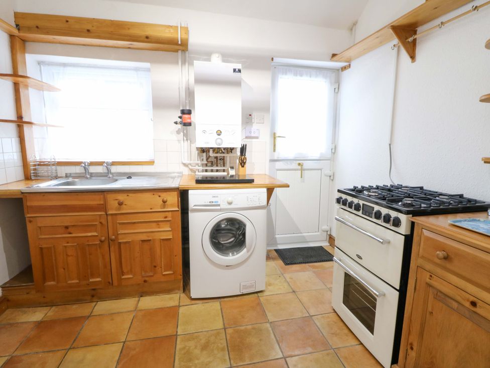 A kitchen with a sink, washing machine, oven, and stove at No.23 Queen St Aberystwyth