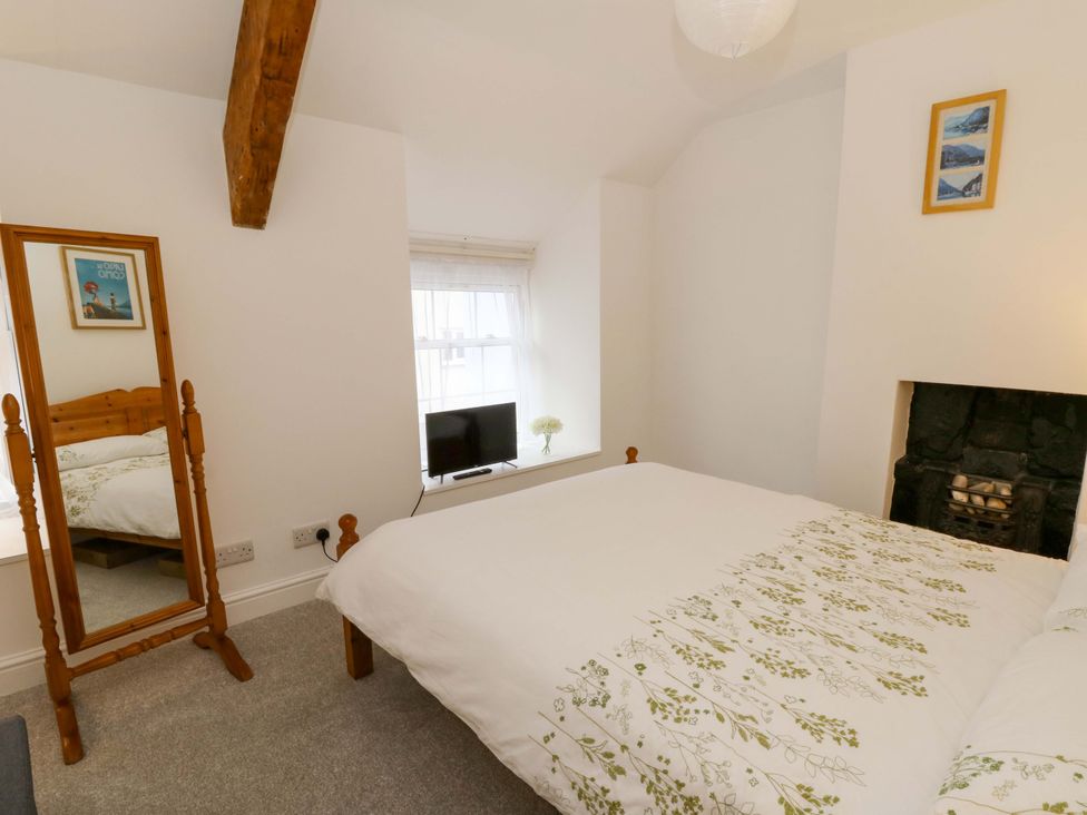 A bedroom with a bed, mirror, and television at No.23 Queen St in Aberystwyth