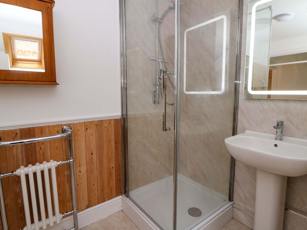 A bathroom featuring a shower, washbasin, and mirror at No.23 Queen St, Aberystwyth