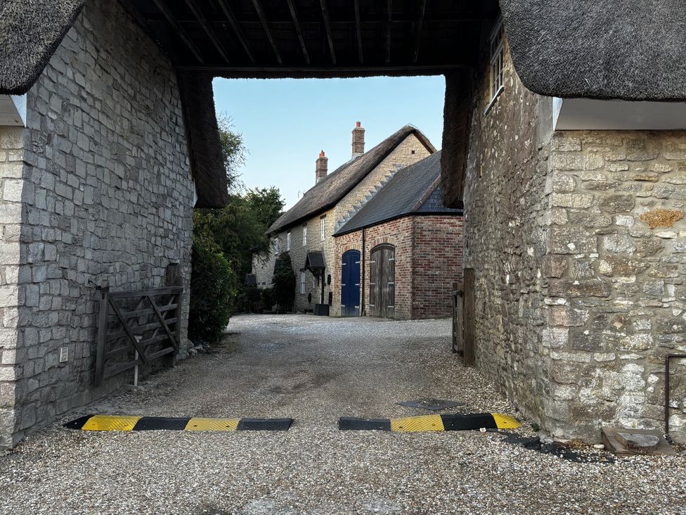 An outdoor area with stone walls and a thatched roof at Bracken Cottage
