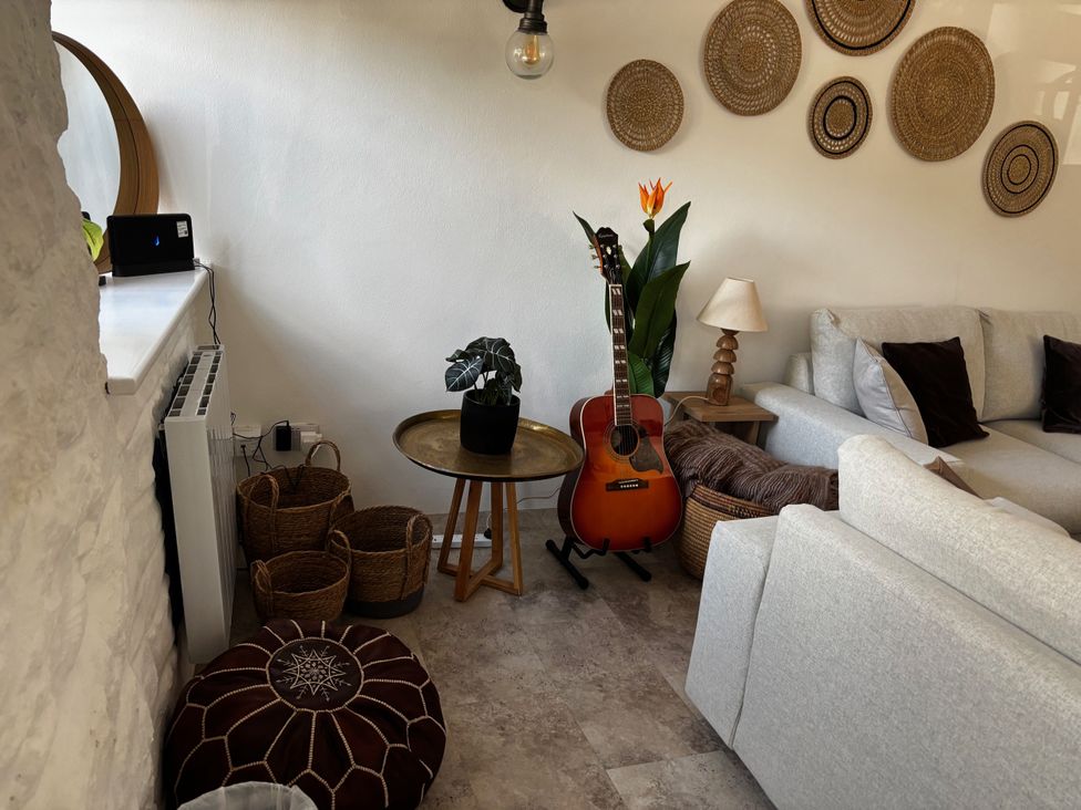 A living room with a guitar and plants at Bracken Cottage in Osmington