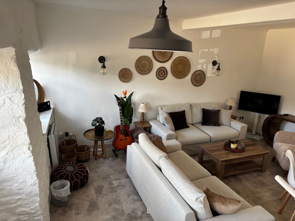 A living room with a sofa, coffee table, and television at Bracken Cottage in Osmington