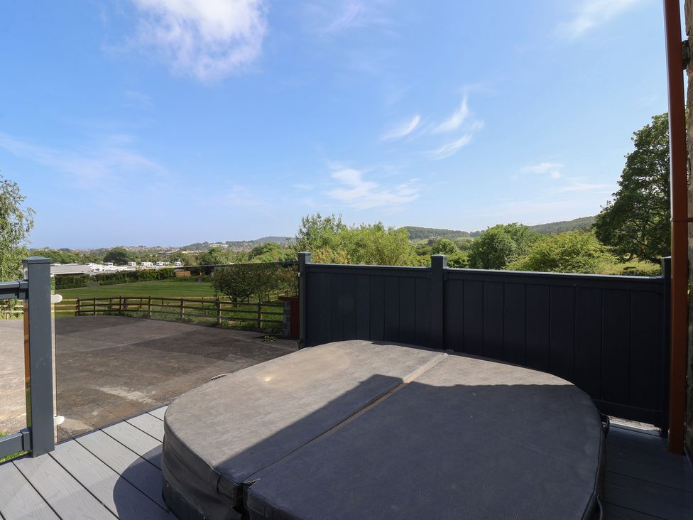 A hot tub on a deck with a view of trees and fields at Birch Cottage in Scarborough