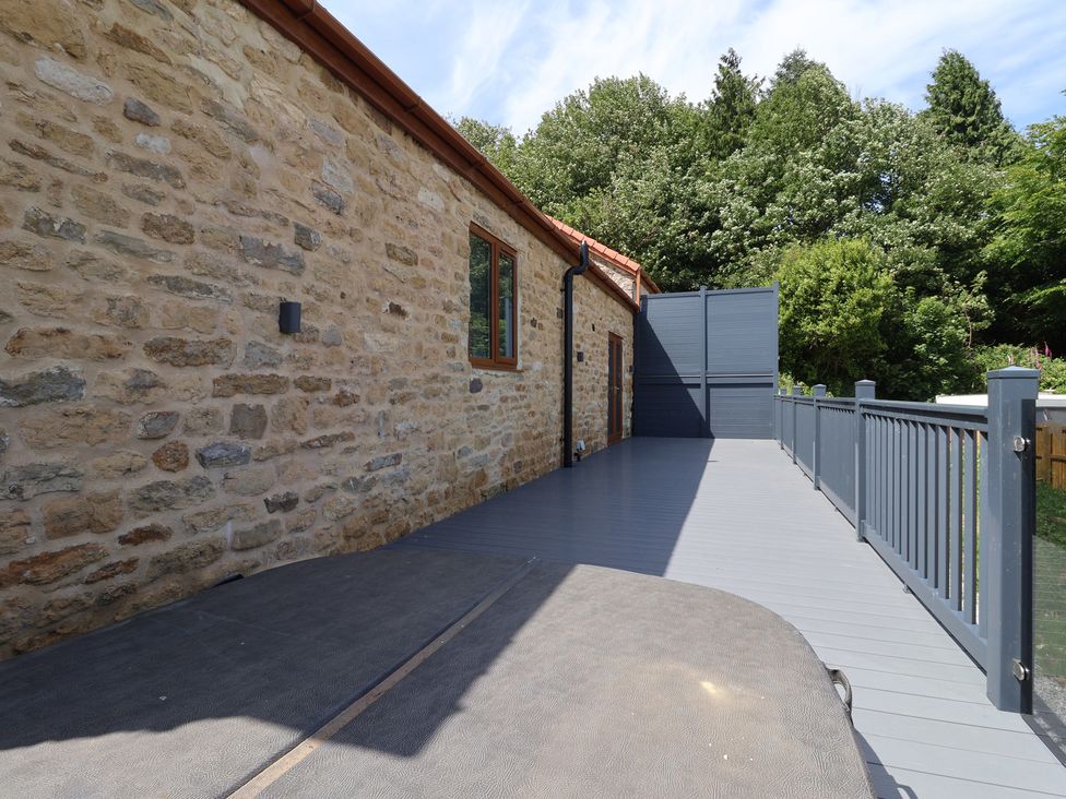 An outdoor area with a stone wall and wooden decking at Birch Cottage in Scarborough