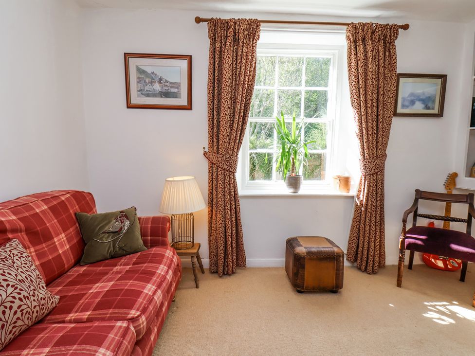 A sitting room with a red plaid sofa cushions a lamp and framed pictures at Whinstone Cottage Esk Valley near Grosmont