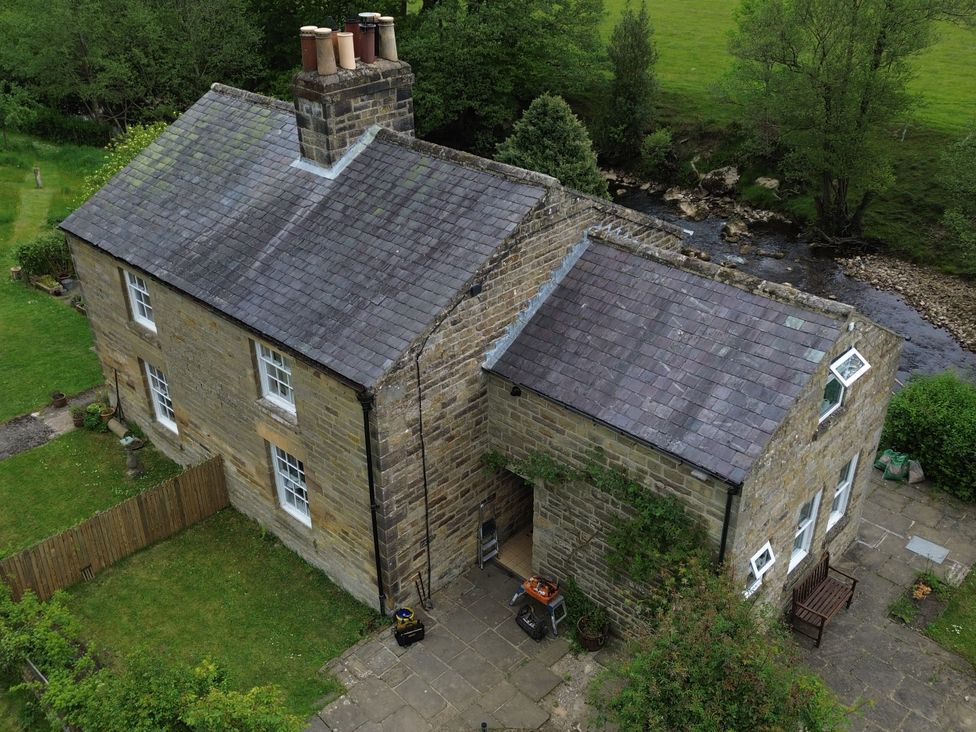 An aerial view of a house with a garden and stream at Whinstone Cottage Esk Valley near Grosmont