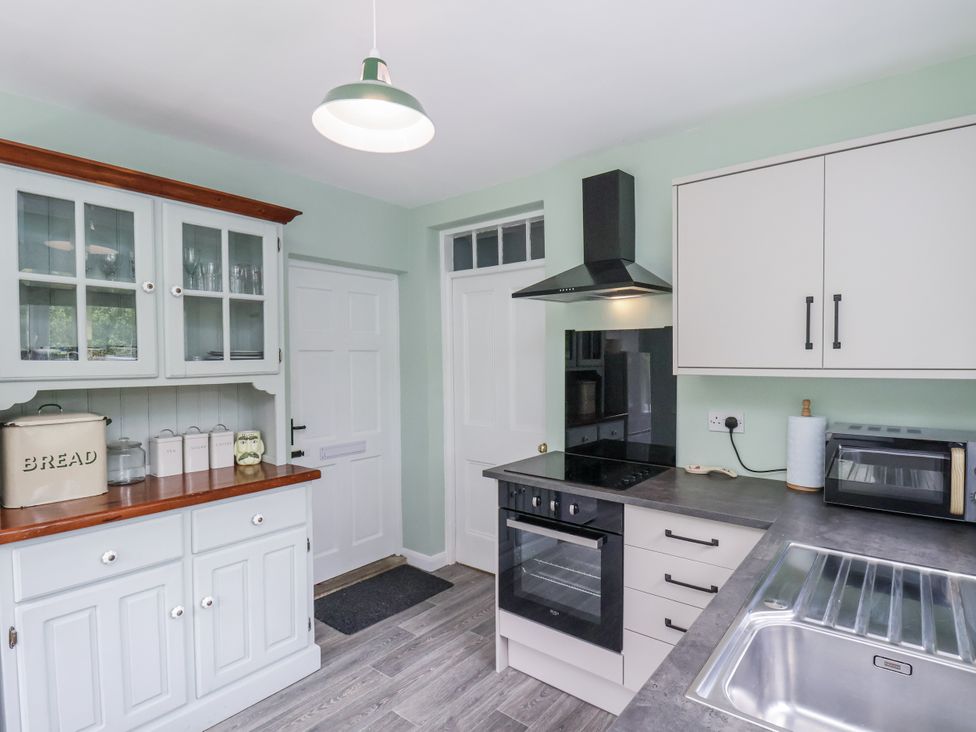 A kitchen with cabinets, oven, sink, and microwave at Whinstone Cottage in Esk Valley near Grosmont