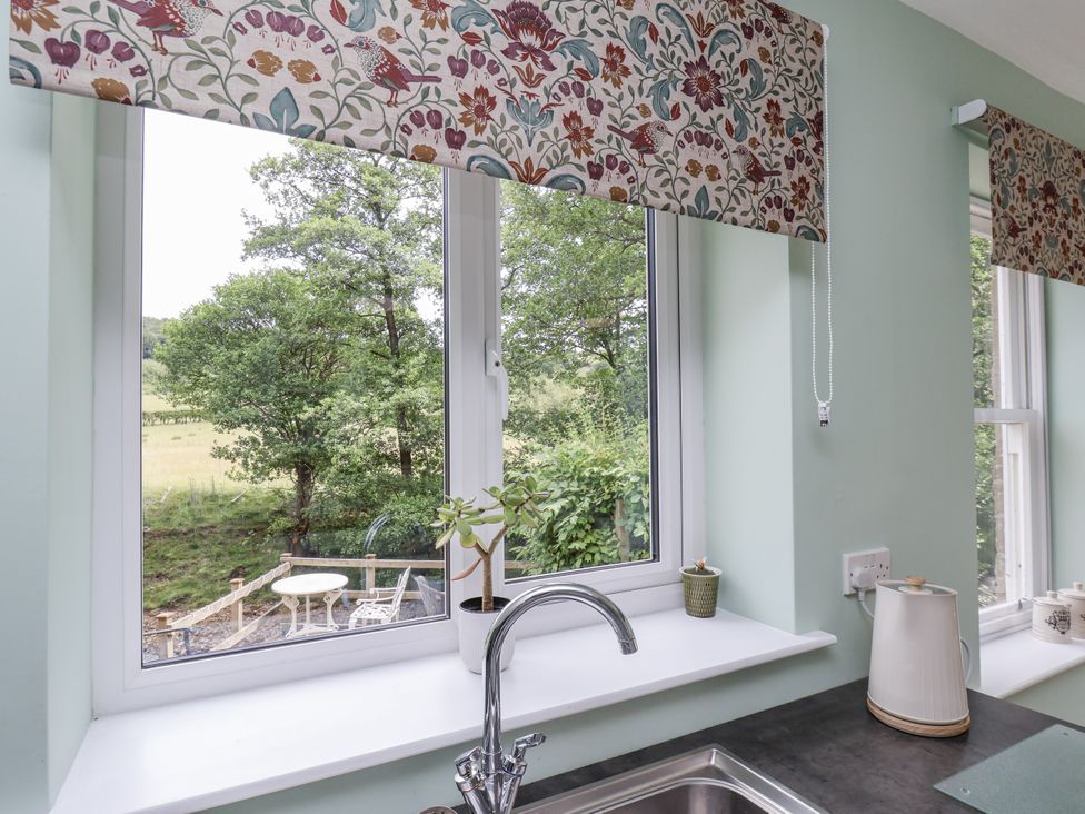 A kitchen window with a view of trees at Whinstone Cottage in Esk Valley near Grosmont