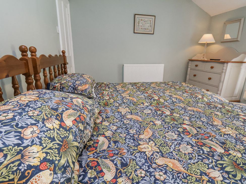 A bedroom with a bed and chest of drawers at Whinstone Cottage in Esk Valley near Grosmont