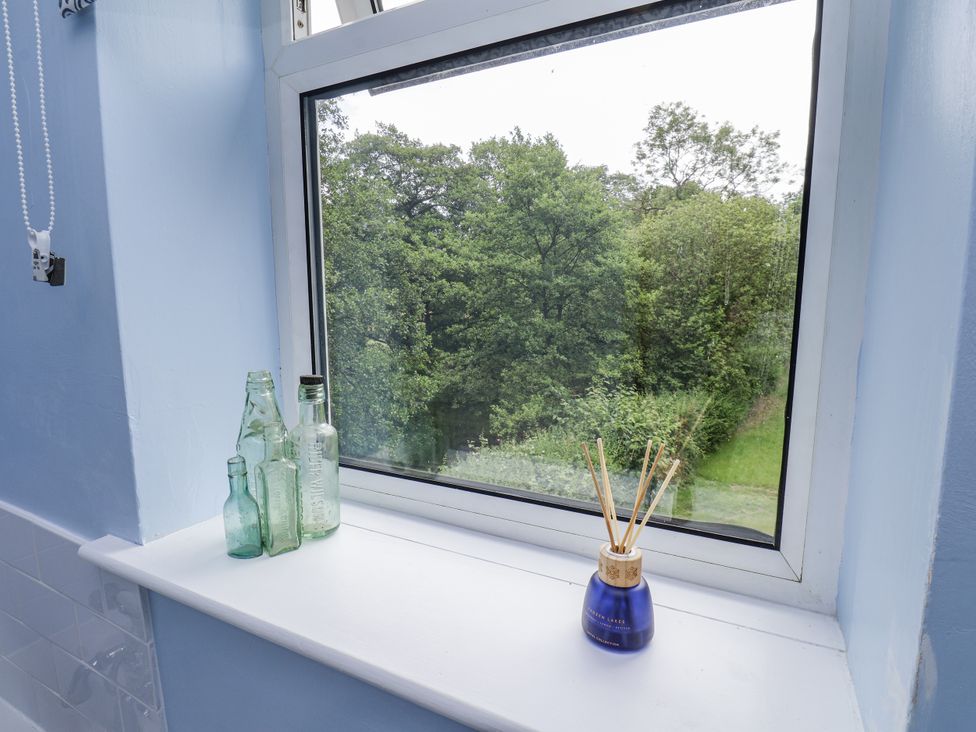 A window with bottles and a view of trees at Whinstone Cottage Esk Valley near Grosmont