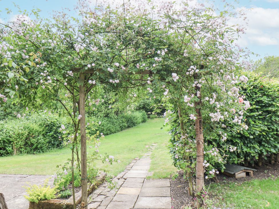 A garden with an archway covered in flowers at Whinstone Cottage Esk Valley near Grosmont