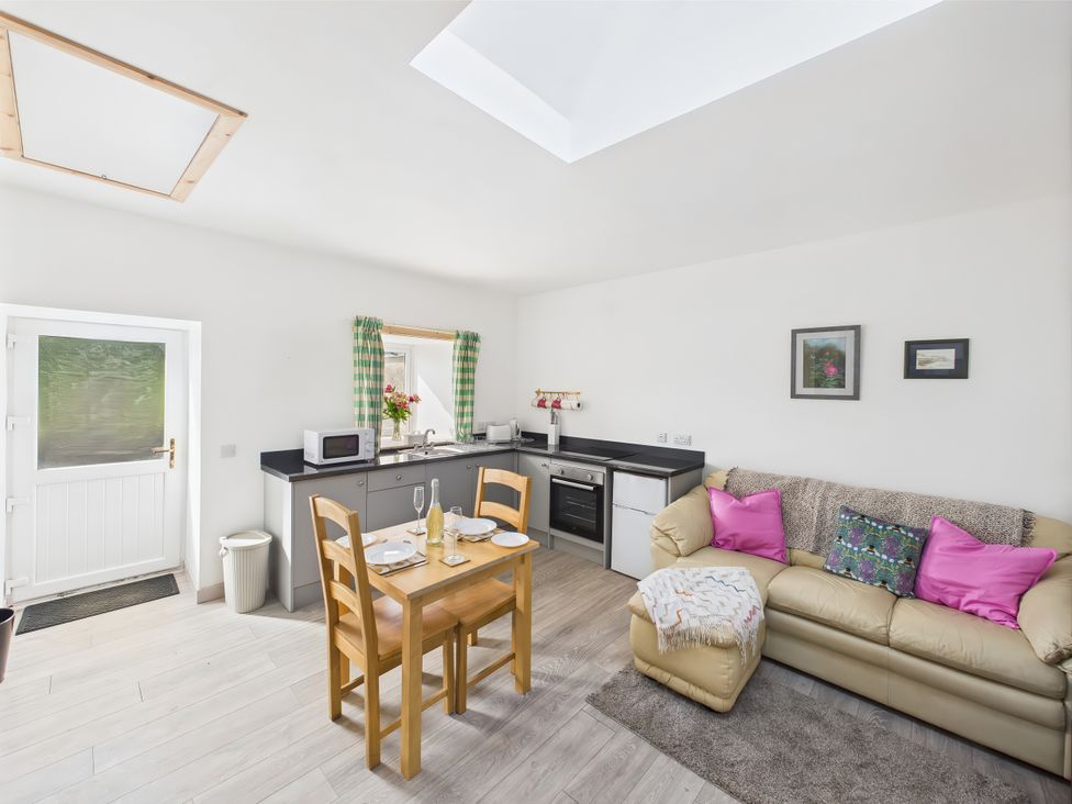 A kitchen with a dining table and couch at Bathach Beag, Balvicar, Isle Of Seil