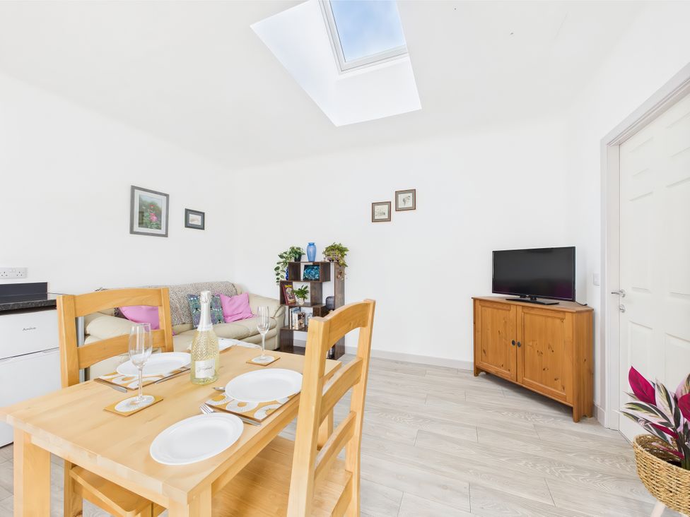 A living room with a table set for dining and a TV at Bathach Beag in Balvicar, Isle Of Seil