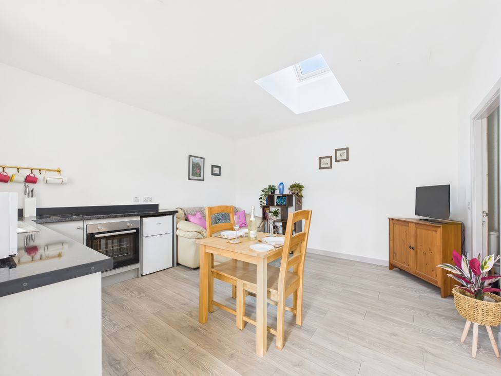 A kitchen with a dining table and a sofa at Bathach Beag in Balvicar, Isle Of Seil