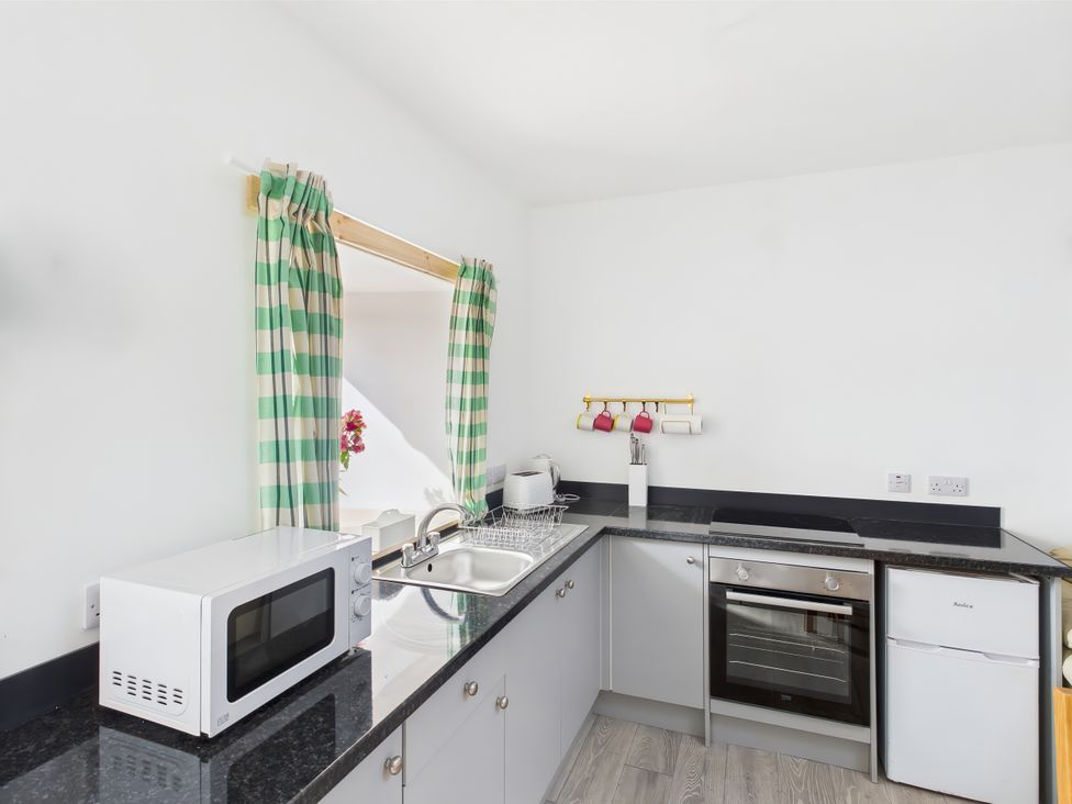 A kitchen with a microwave, sink, and oven at Bathach Beag, Balvicar, Isle Of Seil