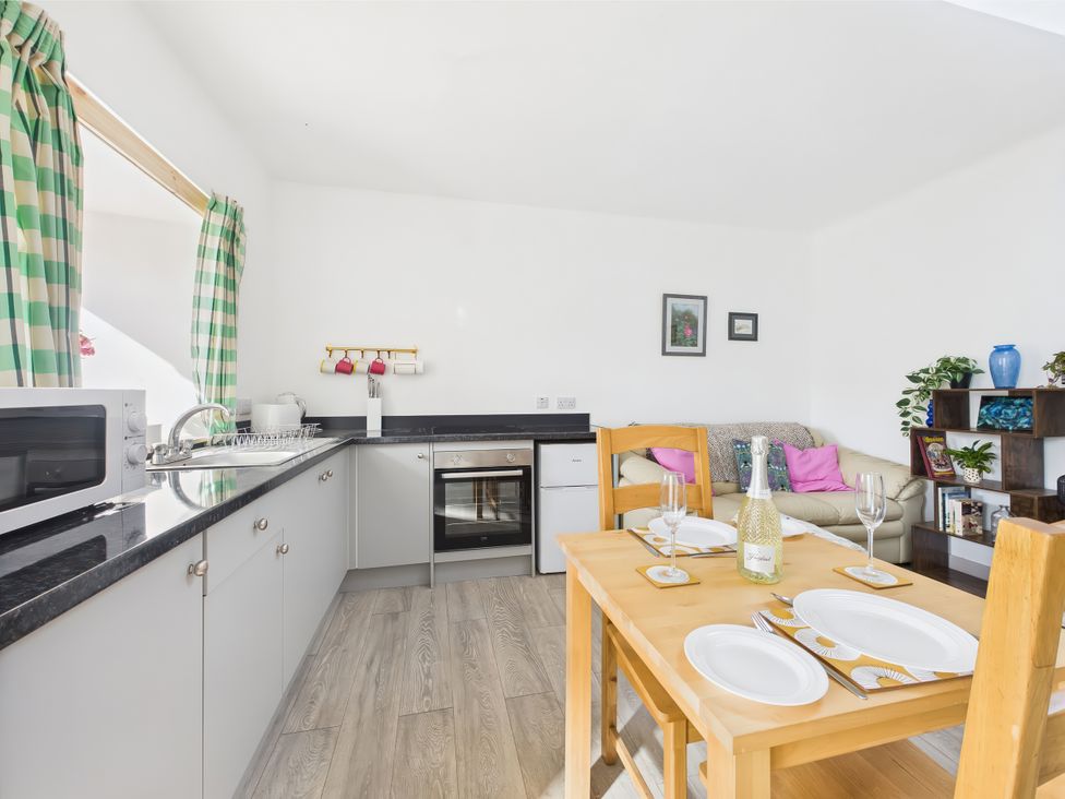 A kitchen with dining table and sofa at Bathach Beag in Balvicar, Isle Of Seil