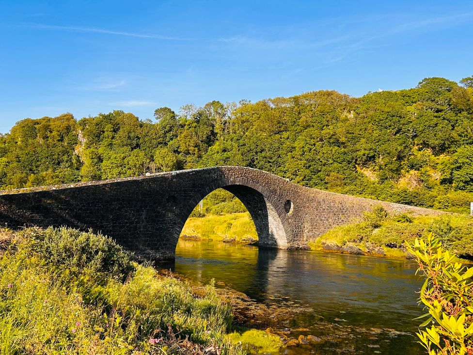 A bridge over a river surrounded by trees at Bathach Beag Balvicar, Isle Of Seil