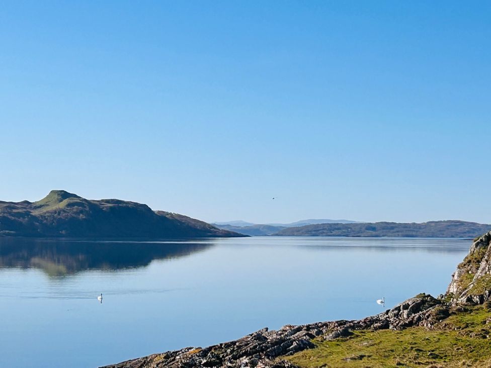 A landscape view of water with islands and mountains at Bathach Beag in Balvicar, Isle Of Seil