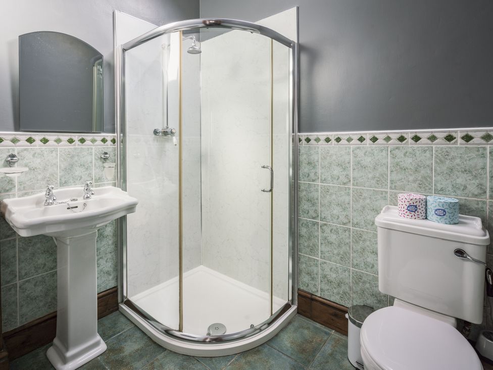 A bathroom with a shower, sink, and toilet at Cove Cottage Llangrannog