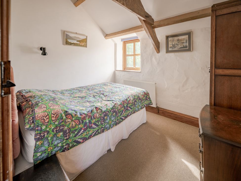 A bedroom with a bed and window at Cove Cottage in Llangrannog