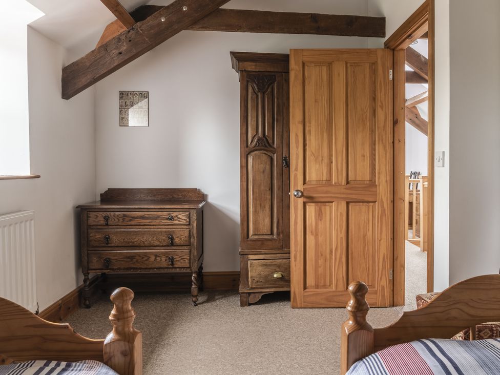 A bedroom with wooden furniture and a door at Y Bwthyn in Llangrannog