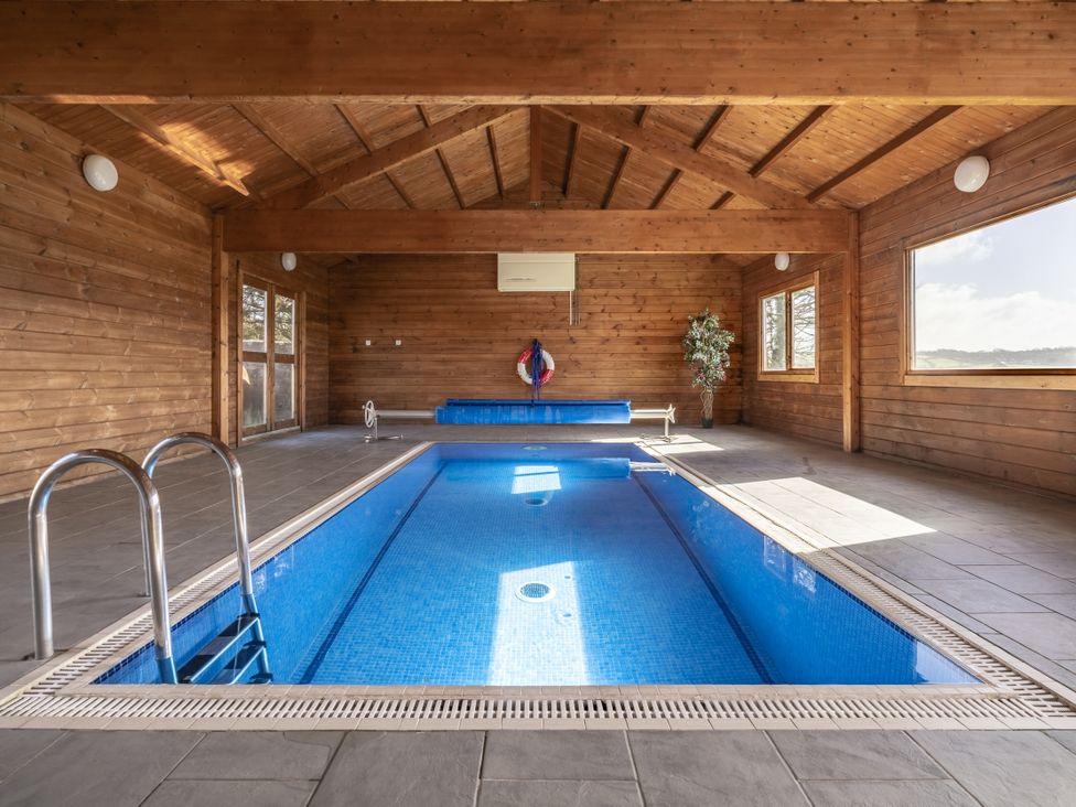 An indoor pool area with a swimming pool and seating at Y Bwthyn Llangrannog