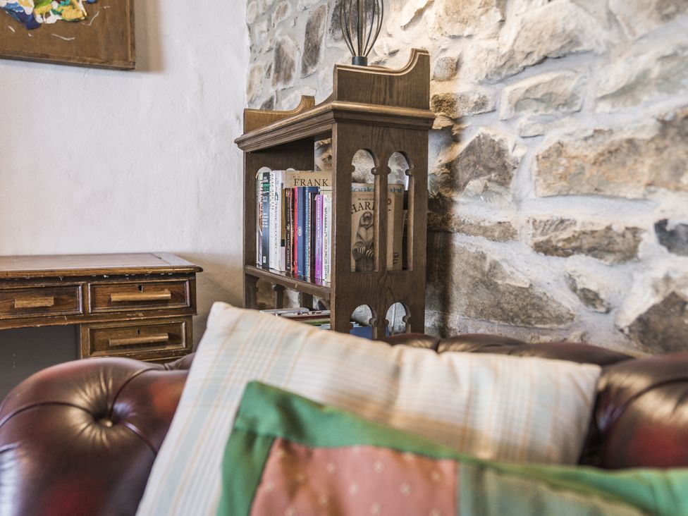 A living room with a bookcase and desk at Coach House in Llangrannog