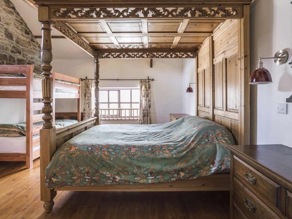 A bedroom with a four-poster bed and a bunk bed at Coach House in Llangrannog