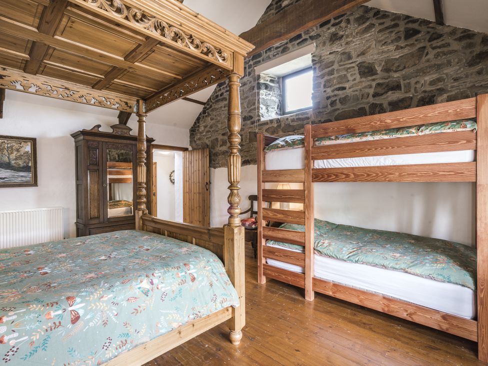 A bedroom with a four-poster bed and a bunk bed at Coach House in Llangrannog